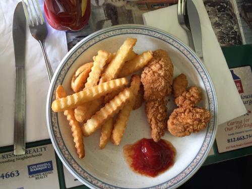 A plate of crispy fried chicken pieces with crinkle-cut fries and a small serving of ketchup.