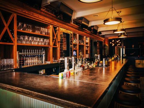A stylish bar with wooden shelves, glassware, and a polished countertop, illuminated by warm lighting.