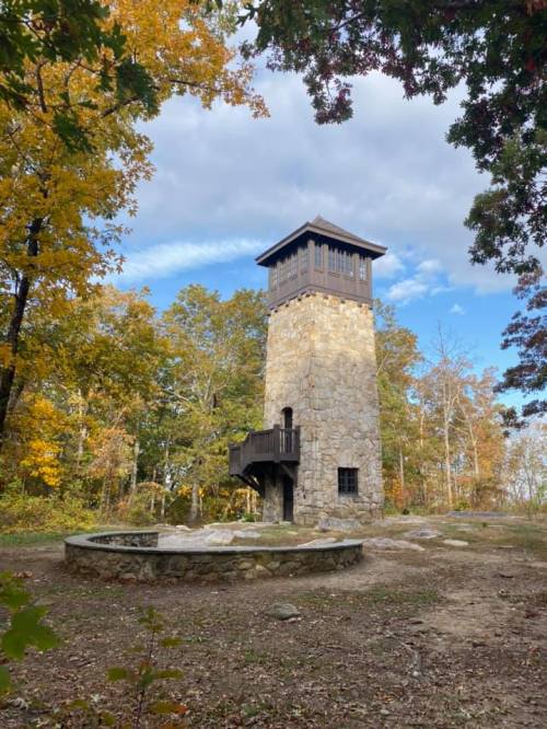 A stone observation tower surrounded by autumn trees and a circular stone seating area.