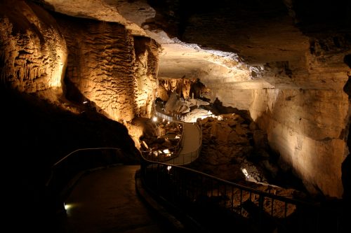 A dimly lit cave interior with a winding pathway and illuminated rock formations.