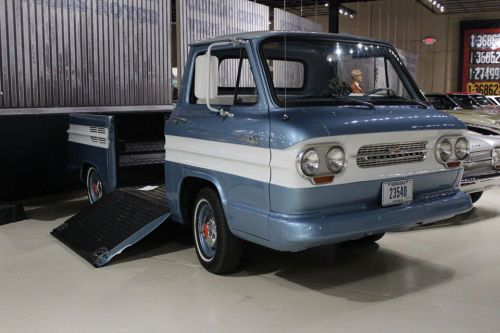 A vintage blue and white pickup truck with a ramp, displayed in a museum setting.