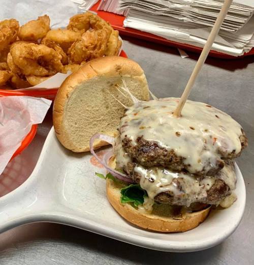 A double cheeseburger with melted cheese, lettuce, and onions, served with a side of crispy fried shrimp.