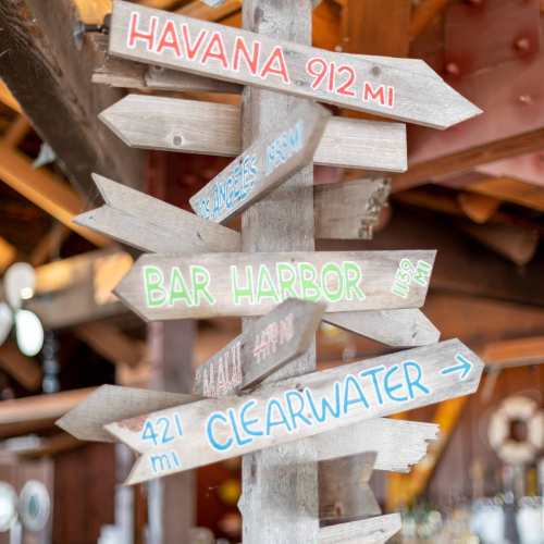 Wooden signpost with directional arrows pointing to various locations: Havana, Bar Harbor, Maui, and Clearwater.