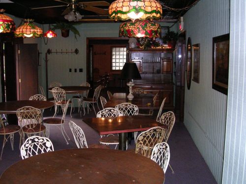 A cozy dining area with wooden tables, vintage chairs, and stained glass lamps, featuring a warm, inviting atmosphere.
