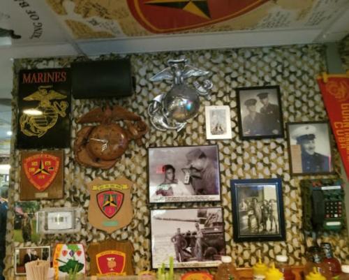 A wall decorated with military memorabilia, including photos, insignias, and a Marine Corps emblem.