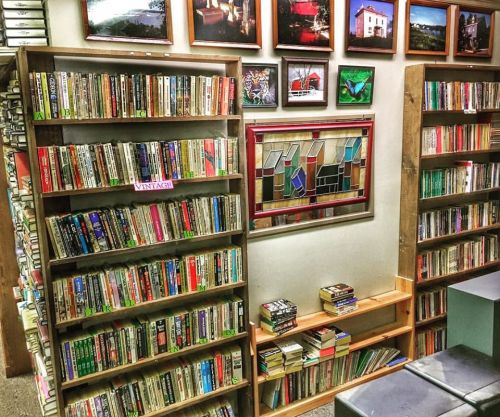 A cozy bookstore with wooden shelves filled with books and framed artwork on the walls.
