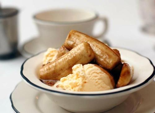 A bowl of sliced bananas topped with vanilla ice cream and a drizzle of caramel sauce.