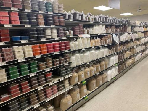 A grocery aisle filled with various containers of sprinkles, sugars, and baking ingredients on shelves.