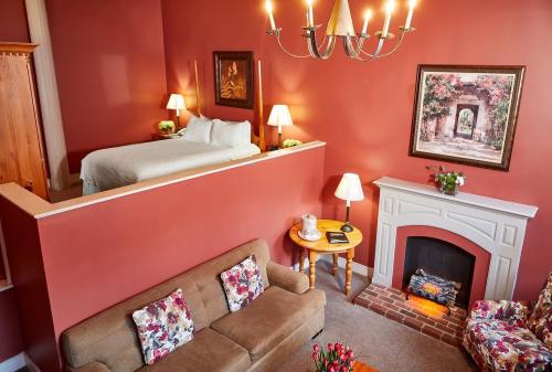 Cozy room with a lofted bed, fireplace, and seating area, featuring warm red walls and floral decor.