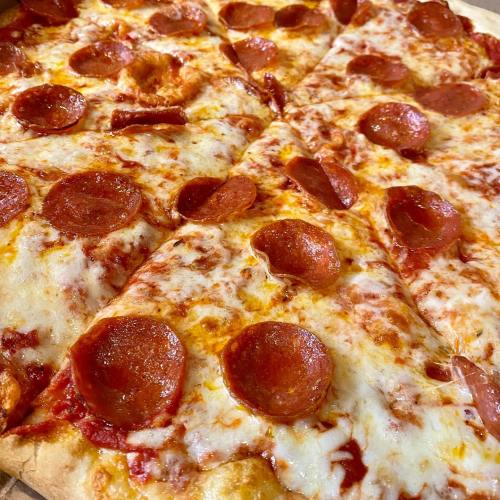 Close-up of a pizza with melted cheese and pepperoni slices on a golden crust.