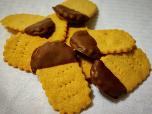 A pile of rectangular cookies, half-dipped in chocolate, arranged on a white surface.