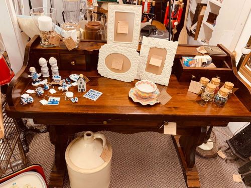A wooden table displaying various vintage items, including frames, ceramics, and small collectibles.