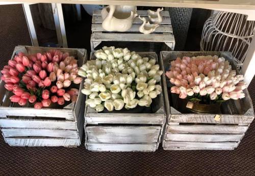 Three wooden crates filled with vibrant artificial flowers: pink, white, and a mix of pink and white tulips.