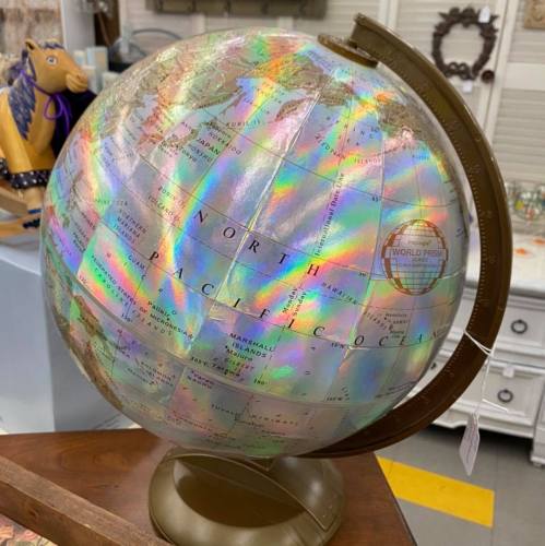 A colorful, iridescent globe on a stand, displaying continents and oceans with a vintage aesthetic.