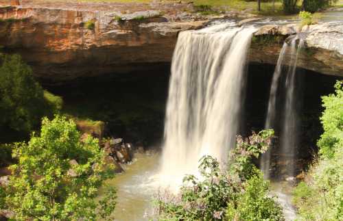 A scenic waterfall cascading over rocky cliffs, surrounded by lush greenery and a tranquil pool below.