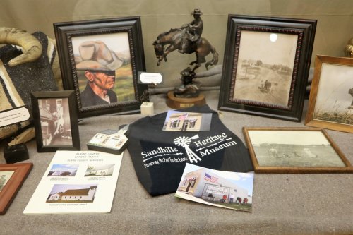 Display case featuring historical photos, a cowboy statue, and memorabilia from the Sandhills Heritage Museum.