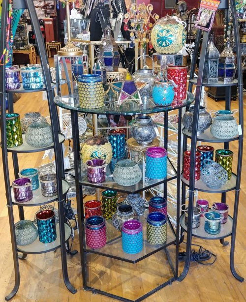 A display of colorful decorative candle holders in various shapes and sizes on a metal stand.