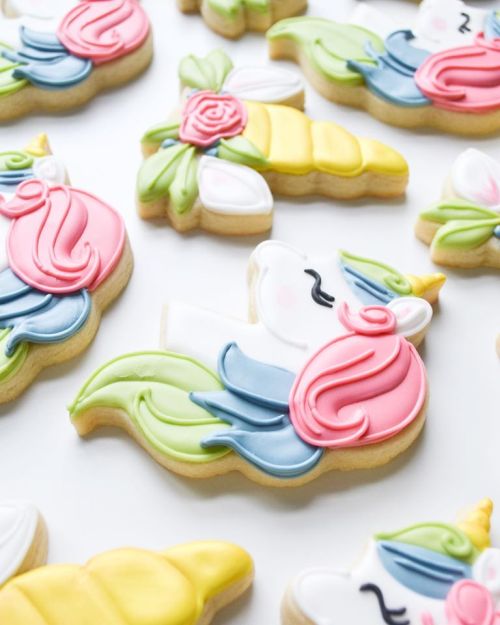 Colorful unicorn-shaped cookies decorated with vibrant icing in pink, blue, green, and yellow.