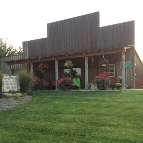 A rustic wooden building with flower pots and a green door, surrounded by a well-maintained lawn and garden.