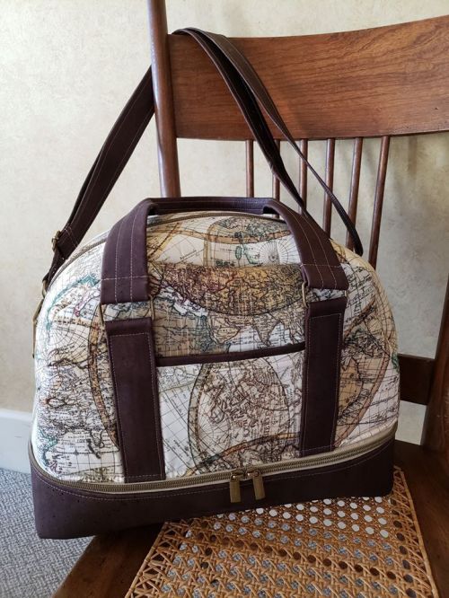 A stylish duffel bag with a vintage map design, resting on a wooden chair.