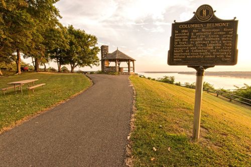 A scenic view of the Mississippi River with a gazebo and historical marker about Columbus-Belmont in the background.
