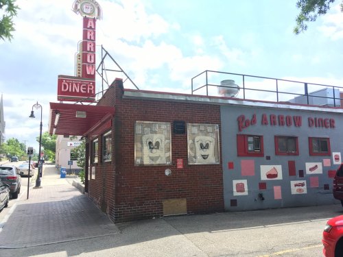 Exterior of Red Arrow Diner featuring a vintage sign, colorful murals, and a brick facade on a sunny day.