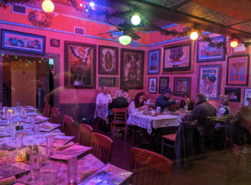 A vibrant restaurant interior with colorful lighting, decorated walls, and diners at tables enjoying their meals.