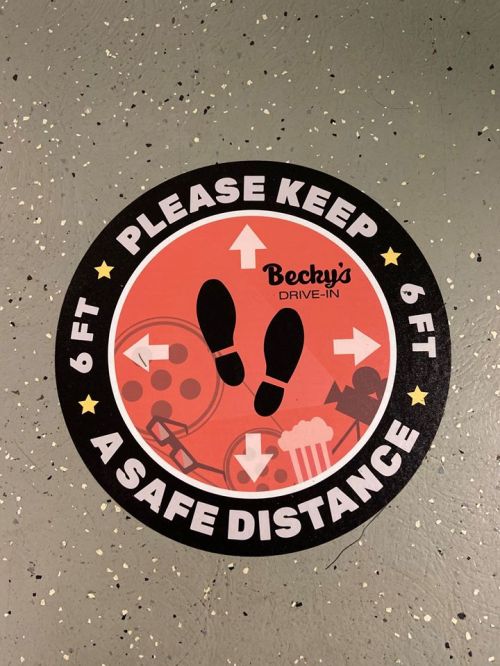 Circular floor sticker at Becky's Drive-In, urging visitors to keep a 6 ft distance with footprints and directional arrows.
