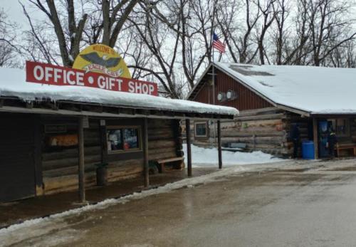 Log cabin gift shop and office with a snowy landscape and an American flag in the background.