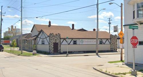 A quaint building with a stone and wood facade at a street corner, featuring a sign for "Darjune Cafe."