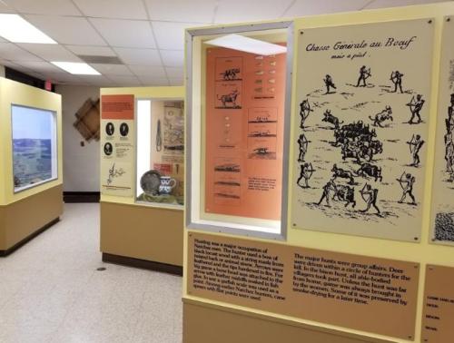 Exhibit showcasing historical hunting practices with informative panels and illustrations in a museum setting.