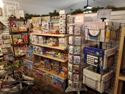 A cozy shop display featuring shelves filled with toys, games, and greeting cards, decorated for the holidays.