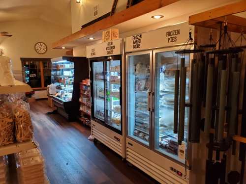 Interior of a store featuring refrigerated units with frozen foods, pies, and a variety of packaged goods on shelves.