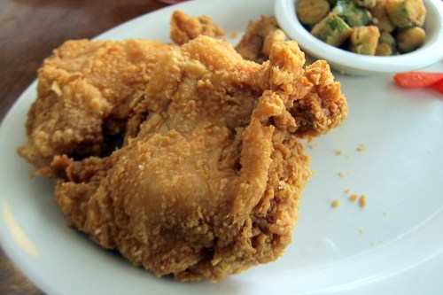 Crispy fried chicken pieces served on a plate with a side of okra.