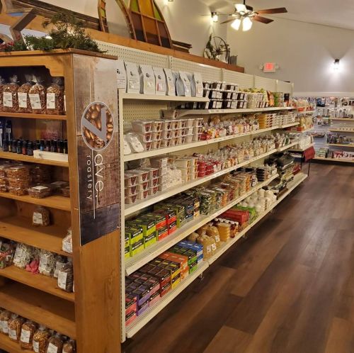 A well-stocked store aisle featuring various snacks, candies, and packaged goods on wooden shelves.