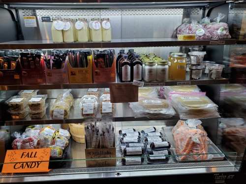 A display case filled with various packaged foods, including candies, sauces, and jars, labeled "Fall Candy."