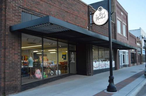 Exterior of a brick building with large windows, featuring a sign for a toy store and colorful displays inside.