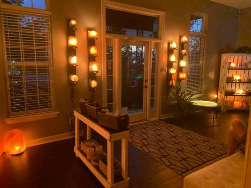Cozy living room with warm lighting, candles on walls, and a stylish table with decorative items.