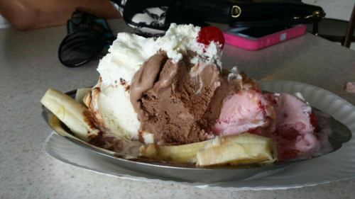 A banana split topped with chocolate, strawberry, and vanilla ice cream, whipped cream, and a cherry.