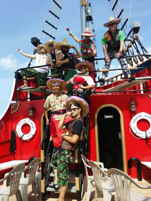 A group of people in colorful outfits and sombreros posing on a red ship, enjoying a festive atmosphere.