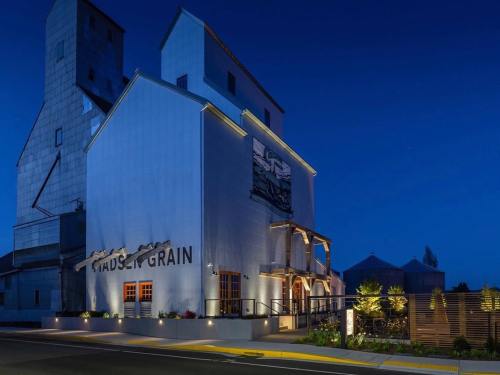 Historic grain elevator building illuminated at night, featuring modern architecture and surrounding greenery.