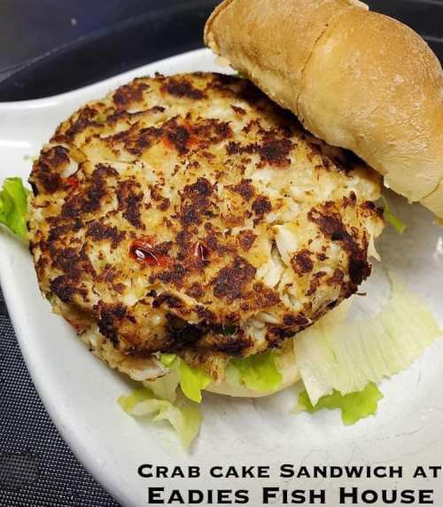 A crab cake sandwich with lettuce on a plate, served with a soft bun at Eadies Fish House.