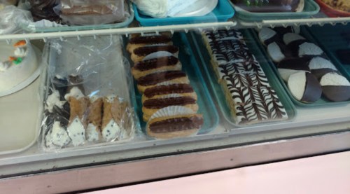 A display case filled with various pastries, including cookies and cream-filled treats, arranged neatly on trays.