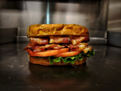 A stacked sandwich with crispy bacon, fresh lettuce, and tomato, served on toasted bread.