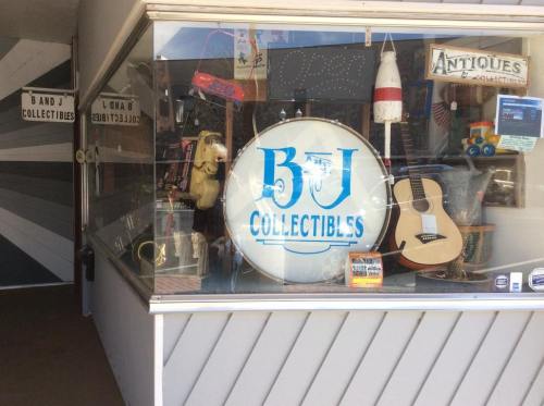 A storefront window displays a sign for "B & J Collectibles" alongside various antiques and collectibles.