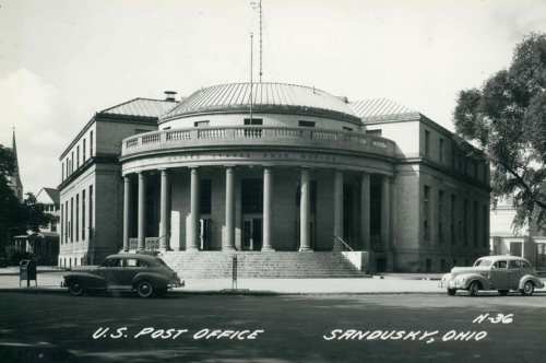 Historic U.S. Post Office building in Sandusky, Ohio, featuring a circular design and vintage cars parked outside.