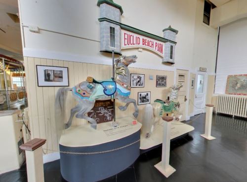 Display of vintage carousel horses from Euclid Beach Park, with historical photos and information on the wall.