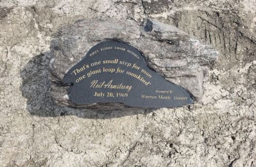 A commemorative plaque on a rock, honoring Neil Armstrong's moon landing quote, dated July 20, 1969.