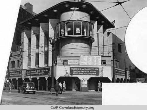 Historic black-and-white photo of a unique building with a rounded roof and large windows, bustling street scene below.