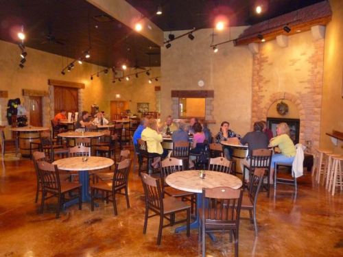 A cozy restaurant interior with wooden tables and chairs, featuring groups of people dining and socializing.